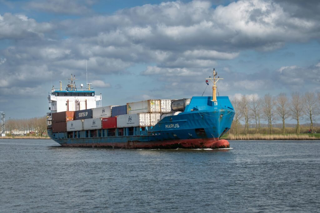 Cargo ship named Marius navigating through calm waters under a scenic cloudscape.